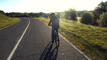 Obraz premium teenager riding a bicycle on the road summer sunlit