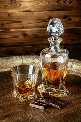 A bottle of cognac and glass on a brown wooden background. Brandy