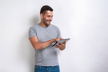 Happy man standing with ipad looking at the screen of it.- Image - obrazy, fototapety, plakaty