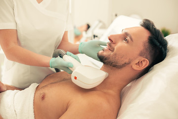 Laser hair removal process on the neck of confident man