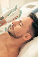 Fototapeta premium Calm face of man at the photo rejuvenation in modern clinic