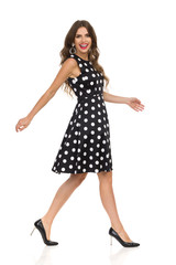 Beautiful Young Woman In Black Dotted Cocktail Dress And High Heels Is Walking And Laughing