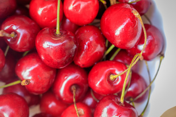 sweet cherry berries in a white plate on a wooden background. Ripe red berries.