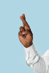 Male hand in white shirt demonstrating a gesture of waiting of good luck isolated on blue studio background. Concept of business, office, work. Negative space to insert your text or image.