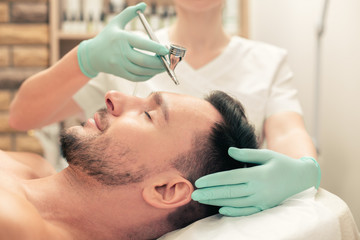 Obraz na płótnie Canvas Oxygen spay treatment of the forehead skin of man