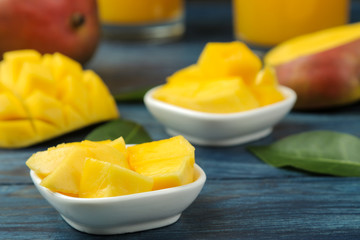 Ripe fresh mango fruit in a basket and slices and leaves on a blue wooden table. tropical fruit.