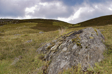 Rock in mountain landscape with steep hills behind