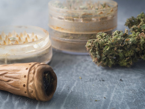 chillum grinder and marijuana lie in the smoke on a wooden table.