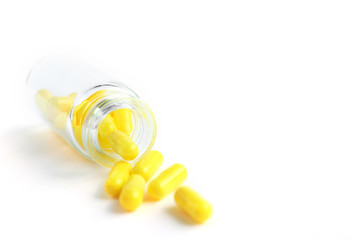 Yellow capsules from glass bottle on white background. copyspace for text. Epidemic, painkillers, healthcare, treatment pills and drug abuse concept