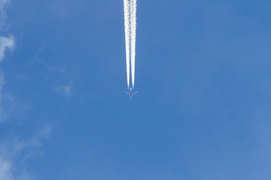 Avion a reaccion volando en el cielo azul. Dejando rastro estela o chorro de vapor de agua, visto desde abajo en plano nadir