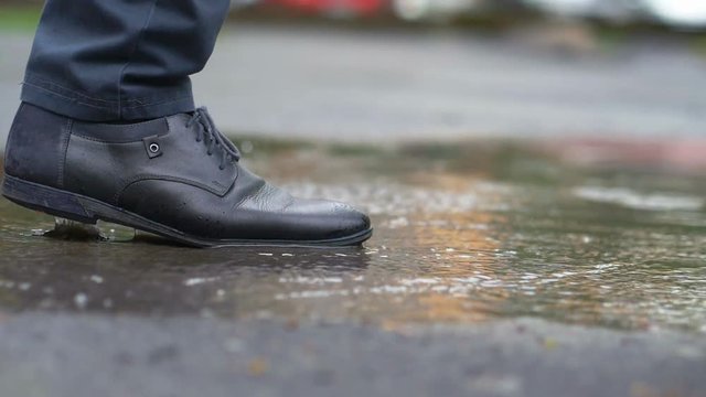 Man in black shoes stepping into the puddle in slow motion 180fps
