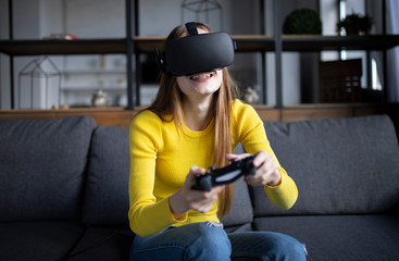 Fototapeta premium Cute girl plays the game on the console. Happy young woman using a virtual reality headset