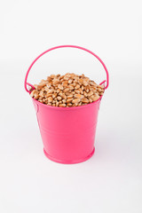 Heap wheat grain in pink bucket on white background.