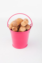 Heap peanut nuts in pink bucket on white background.