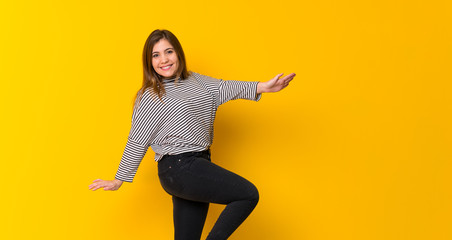 Fototapeta na wymiar Young girl jumping over isolated yellow background