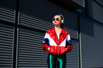Back in time 90s 80s. Stylish girl in retro jacket and vintage cassette player listens to music, fashion trends, entertainment, heat in summer