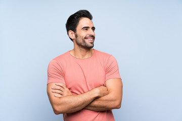 Handsome young man in pink shirt over isolated blue background happy and smiling