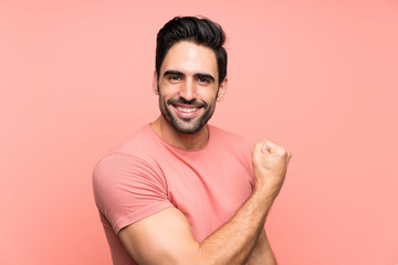 Handsome young man over isolated pink background celebrating a victory