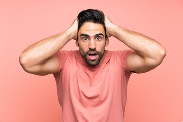 Handsome young man over isolated pink background with surprise facial expression