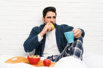 Man in bed with dressing gown and having breakfast