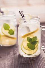 Cold Lemonade with Ice. Lemon and Mint Leaves in Mason Jar on Dark Wooden Background.