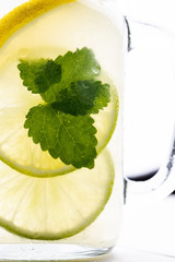 Cold Lemonade with Ice. Lemon and Mint Leaves in Mason Jar on Dark Wooden Background.