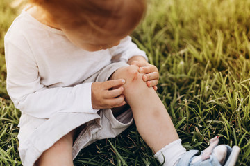 photo of a little girl who fell and scratched his knee in the blood, it hurts the wound and it keeps a handle on the leg, but not crying