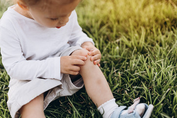 a boy riding a bike or roller, fell and injured his leg. His knee has a scratch and flows in the...