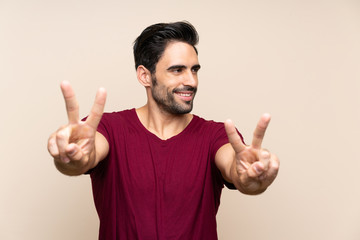 Handsome young man over isolated background smiling and showing victory sign