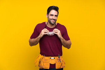 Handsome young craftsman over isolated yellow background