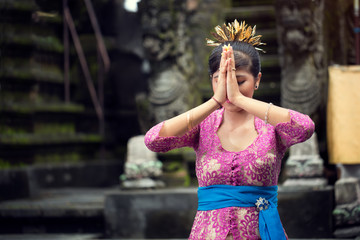 young woman is praying in Balinese temple during