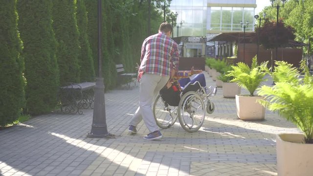 african woman with an afro hairstyle disabled in a wheelchair in the park for a walk with a friend having fun
