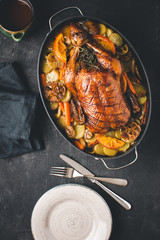 Roasted Goose with Carrots, Oranges and Potatoes on Dark Stone Background