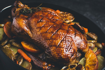 Roasted Goose with Carrots, Oranges and Potatoes on Dark Stone Background