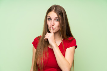 Young woman with long hair over isolated green wall doing silence gesture