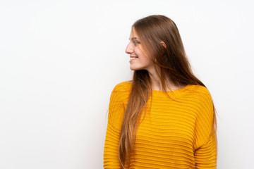 Young woman with yellow over isolated white wall standing and looking to the side