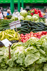 Various fresh vegetables on the marketplace in Belgrade. Blurred sellers and customers on background. Letters 