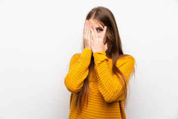 Young woman with yellow over isolated white wall covering eyes and looking through fingers