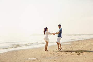 Fototapeta na wymiar Happy couple in love has fun on the beach. They jump, laugh and enjoy the sea