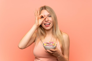 Young woman with popcorns over pink wall makes funny and crazy face emotion