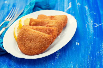 portuguese meat snacks on white dish on blue wooden background