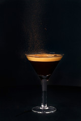 Espresso martini coffee sprinkled with cinnamon on a black background