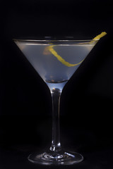 white lady cocktail with zest for taste in a martini glass, shot in classical perspective on a black background
