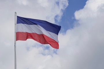 Wehende Flagge von Schleswig-Holstein vor blauem Himmel mit Wolken