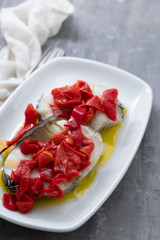 boiled fish with red pepper and olive oil on white dish