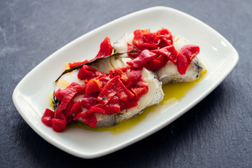 boiled fish with red pepper and olive oil on white dish