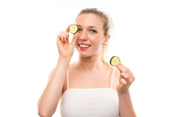 Beautiful young woman holding slices of cucumber over isolated white background