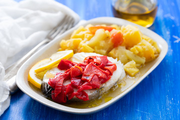boiled fish with red pepper, vegetables and olive oil on white dish