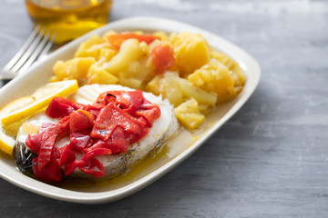 boiled fish with red pepper, vegetables and olive oil on white dish