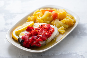 boiled fish with red pepper, vegetables and olive oil on white dish